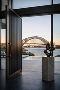 Cast aluminium pivot door opening toward Sydney Harbour Bridge
