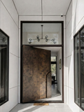 Bronze finish aluminium pivot door with concealed frame and custom sculptural pull handle in modern luxury entrance