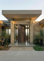 Bronze finish aluminium pivot door with concealed frame and custom sculptural pull handle in modern luxury entrance